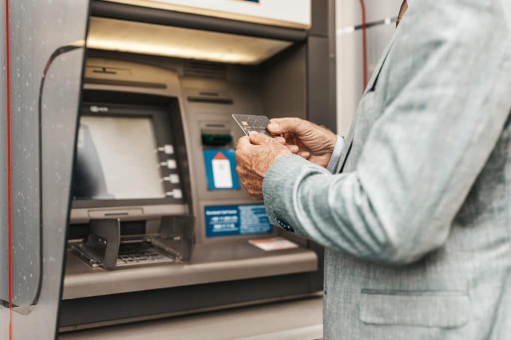 Mies nostamassa käteistä pankkiautomaatilta.