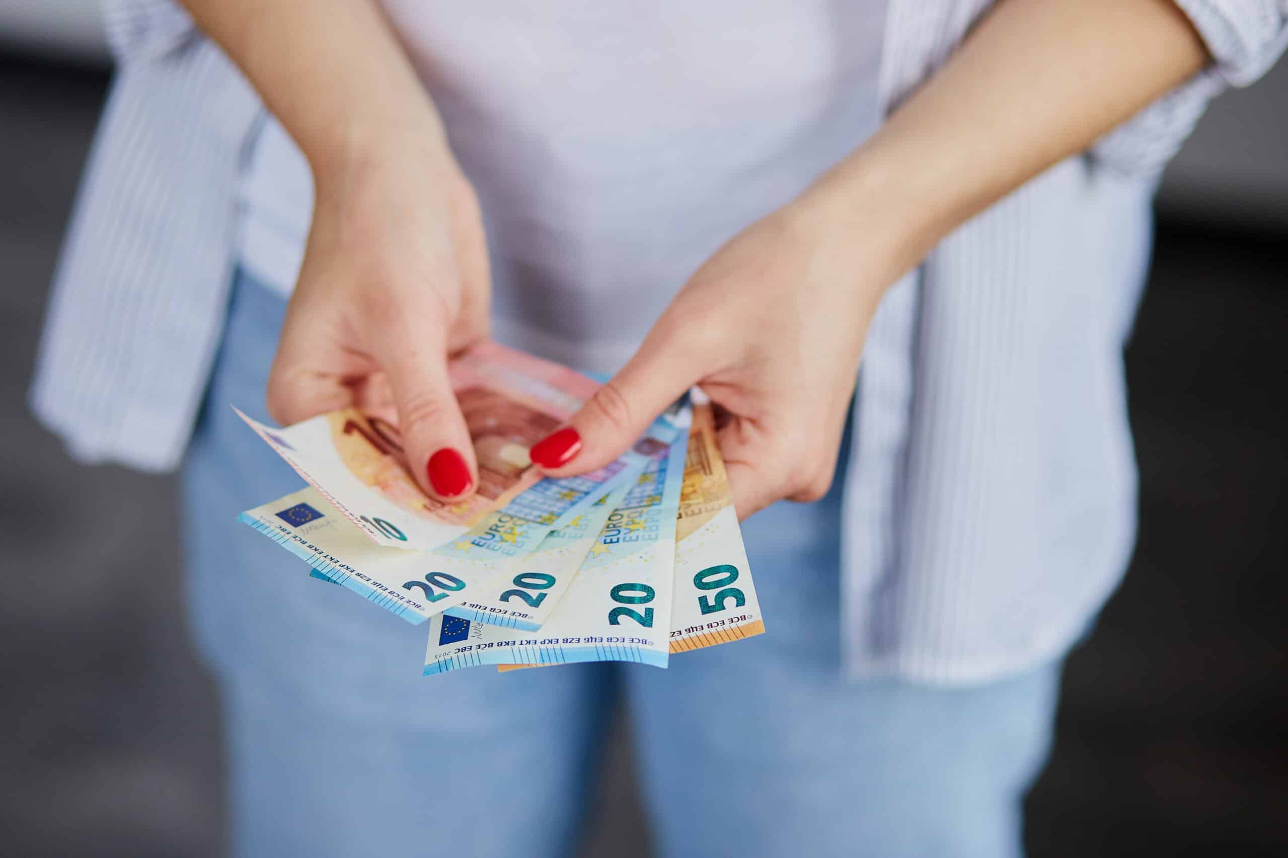 Nainen pitelemässä euron seteleitä käsissään.